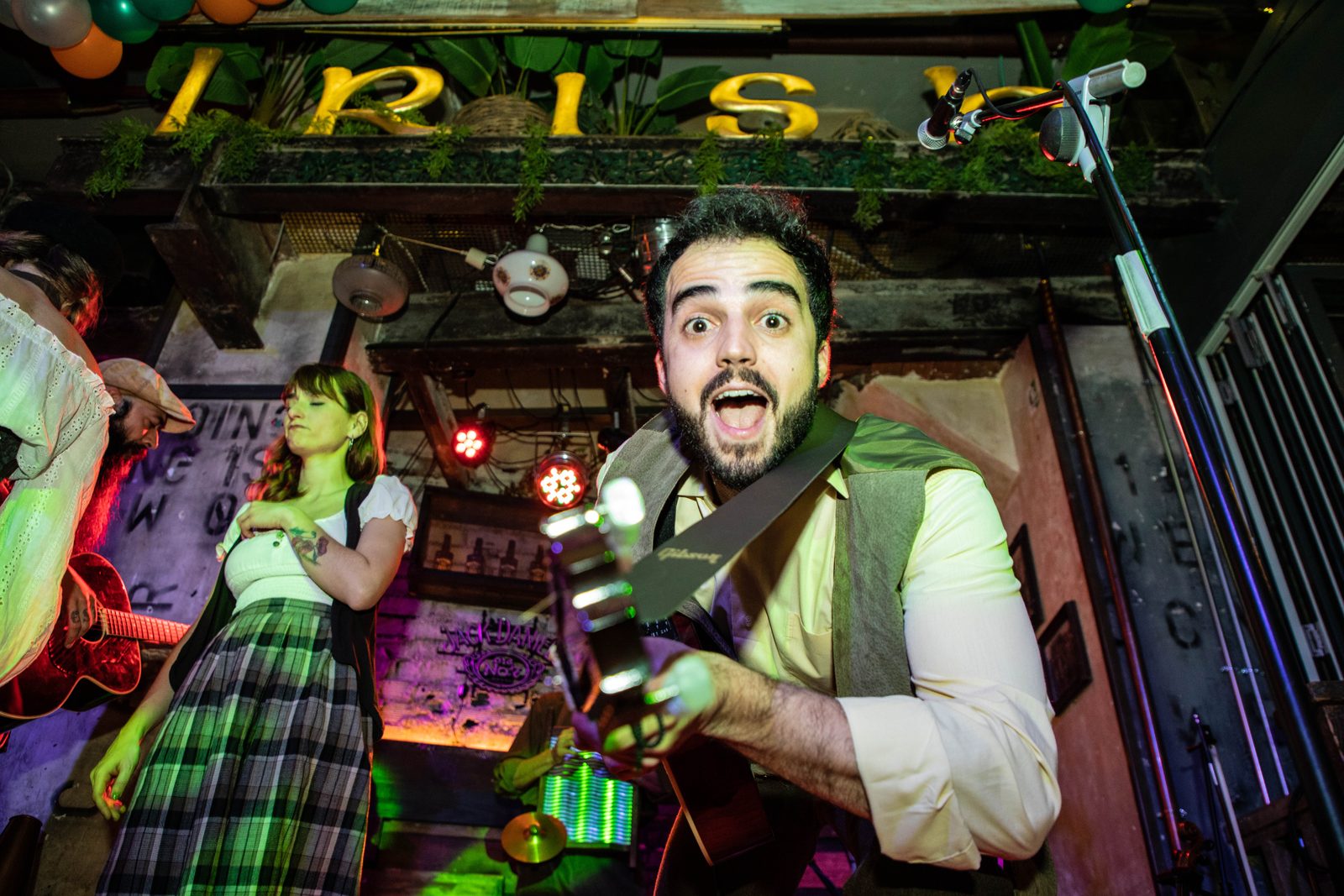 Músico tocando la guitarra bajo el cartel de Irish en un pub